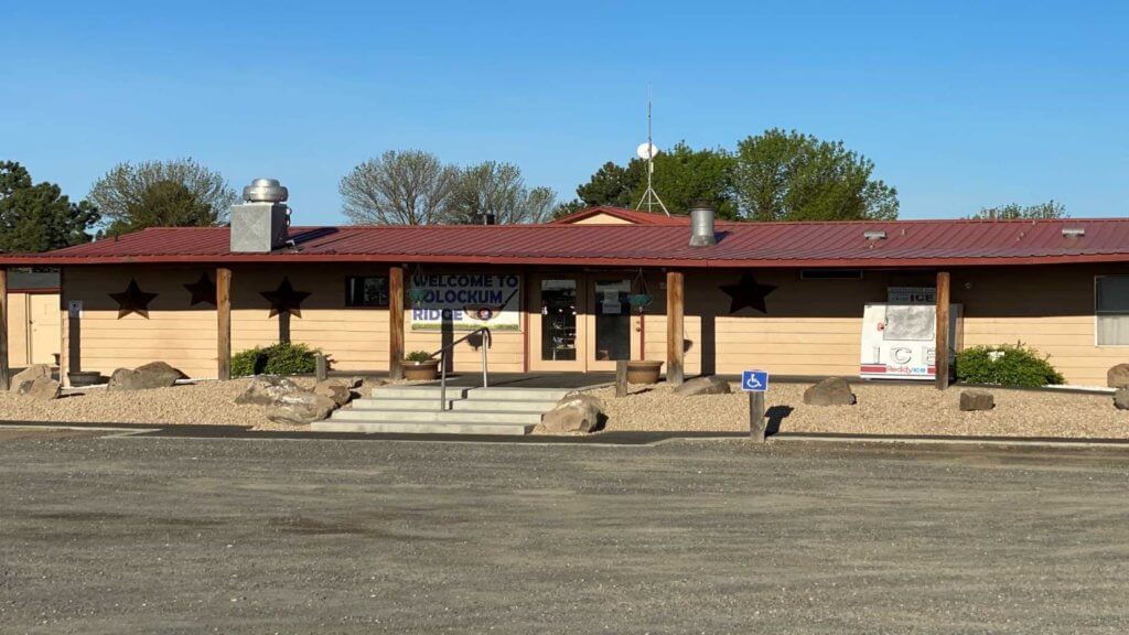 Clubhouse building with parking area and golf carts out front.