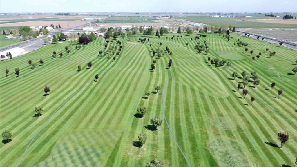 Overhead view of golf course with greens, fairways, and surrounding landscape.