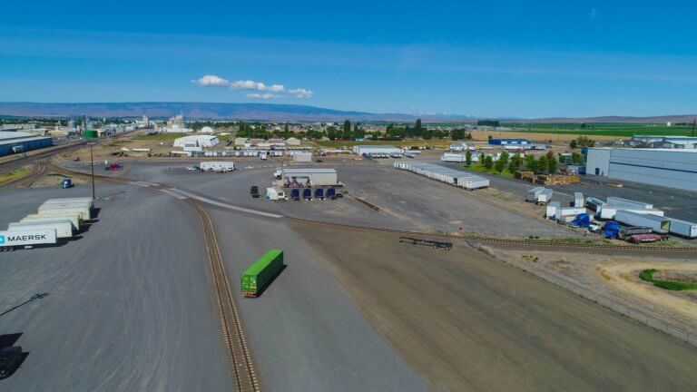 Rail tracks curving through farmland near intermodal site.